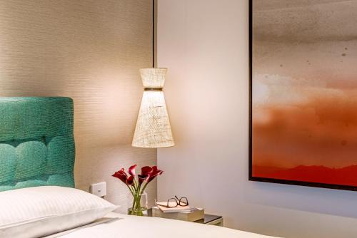 a bedroom with a bed and a lamp and a vase of flowers at Crown Promenade Perth in Perth