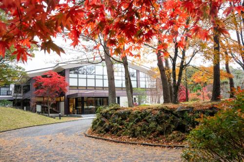 budynek z czerwonymi liśćmi na drzewach i droga w obiekcie Motosu Phoenix Hotel w mieście Fujikawaguchiko