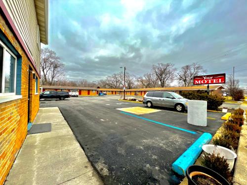 ein Parkplatz mit einem Motelschild und Autos geparkt in der Unterkunft Your Motel in Ypsilanti