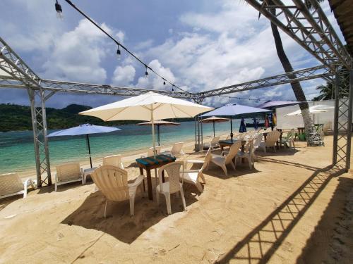 una playa con sillas, mesas y sombrillas en Casa de playa, en Isla Grande