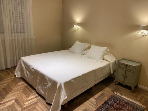 1 dormitorio con 1 cama con sábanas blancas y mesa en Alquiler Temporario En Playa Grande en Mar del Plata
