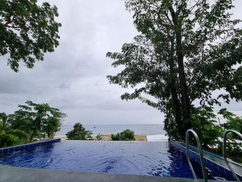 uma piscina com uma árvore e o oceano em Home in Bohol Philippines em Lila