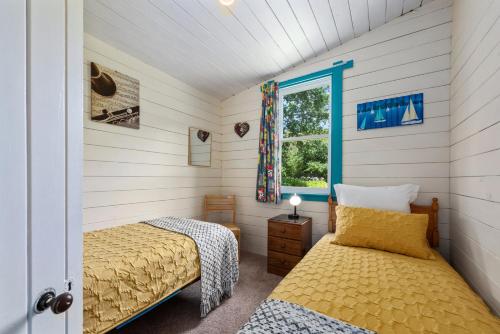 1 Schlafzimmer mit 2 Betten und einem Fenster in der Unterkunft India House & Ica Whare in Whareama, Nr Riversdale Beach in Whareama