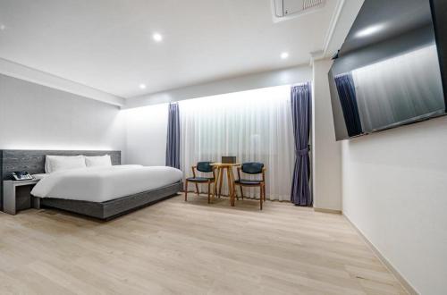1 dormitorio con 1 cama, mesa y sillas en H-Evian Hotel en Gwangju