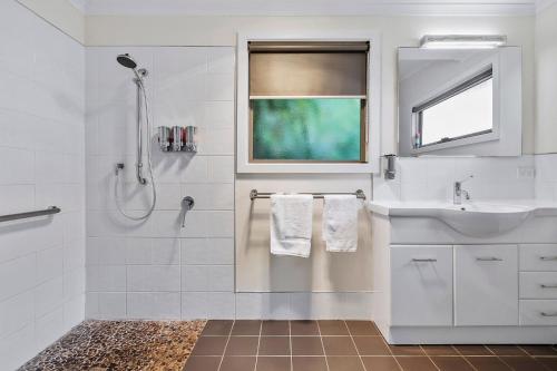 a white bathroom with a sink and a shower at Ocean View Cottages in Dover, Far South Tasmania in Dover
