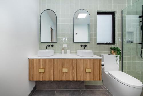 uma casa de banho com 2 lavatórios, uma banheira e um espelho. em Blairgowrie Beach Abode em Blairgowrie