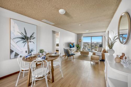 a dining room with a table and chairs and a living room at 2-Bed near Beach with BBQ & Stunning Ocean Views in Alexandra Headland