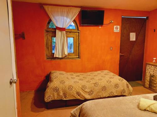 1 dormitorio con paredes de color naranja, 1 cama y ventana en Fuentes Del Valle en Villa Nicolás Romero