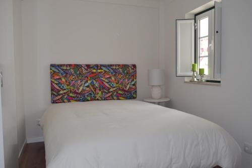 a bedroom with a white bed with a painting on the wall at Acolhedor Apartamento Em Alfama in Lisbon