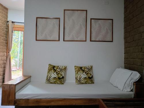 eine weiße Wand mit drei Bildern über einer Couch in der Unterkunft CASA RAÍZ RÍO ANCHO in Mingueo