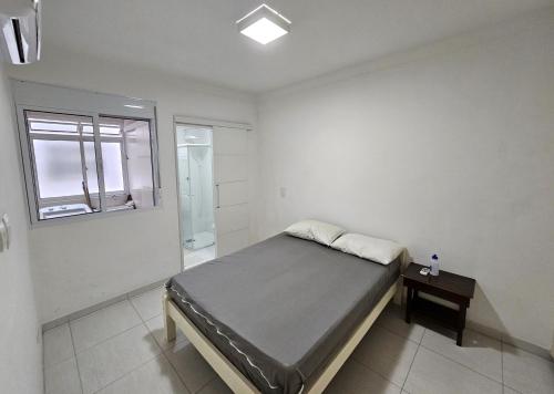 a white room with a bed and a window at Confortável - Praia da Enseada - Beach Host in Guarujá