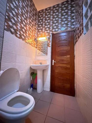 baño con aseo, lavabo y puerta en Quick Apartments, en Cotonou