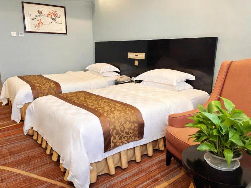 una habitación de hotel con 2 camas y una planta en Skyline Plaza Hotel Guangzhou, en Guangzhou