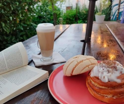een tafel met een bord gebak en een boek en een drankje bij Hostal Casa Violeta in Tepic