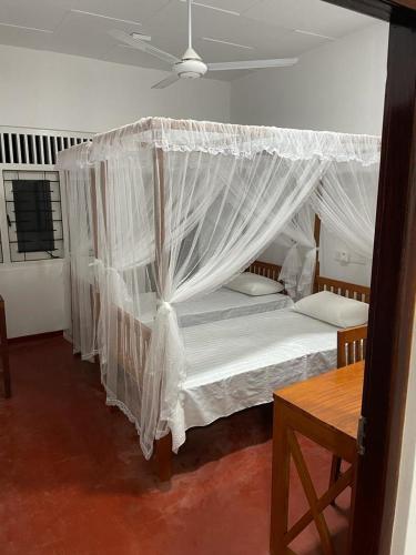 a bedroom with a canopy bed with white drapes at Pacifia Villa in Bentota