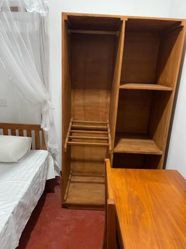 a bedroom with a wooden book shelf next to a bed at Pacifia Villa in Bentota