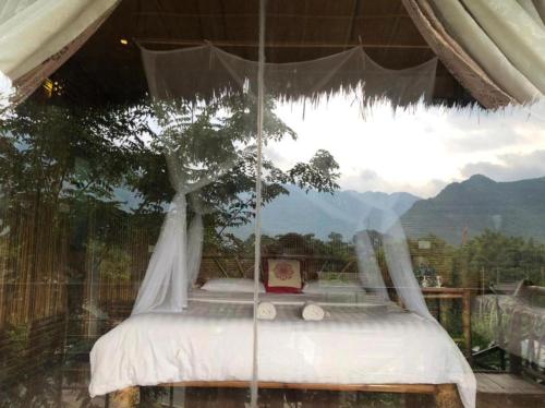 Una cama en una tienda con un árbol. en Eco Homestay Mai Chau - Venuestay, en Mai Chau