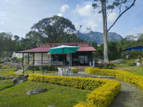 a building with a table and a green umbrella at Villa tata Granja autosostenible in Sasaima