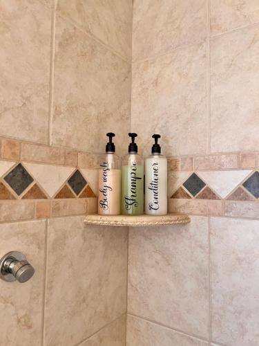 two shampoo bottles sitting on a shelf in a shower at 11640 Gothic Avenue in Los Angeles