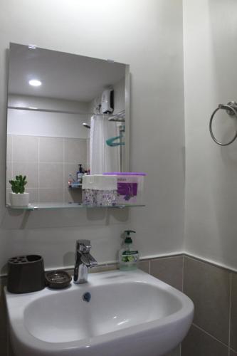 uma casa de banho com um lavatório branco e um espelho. em JP Persimmon Cebu Staycation em Cebu