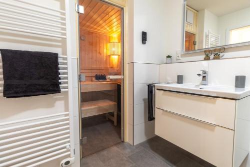een badkamer met een wastafel en een spiegel bij Dorumer Sielhuus 7 - Ferienwohnung mit Terrasse und Sauna in Dorum
