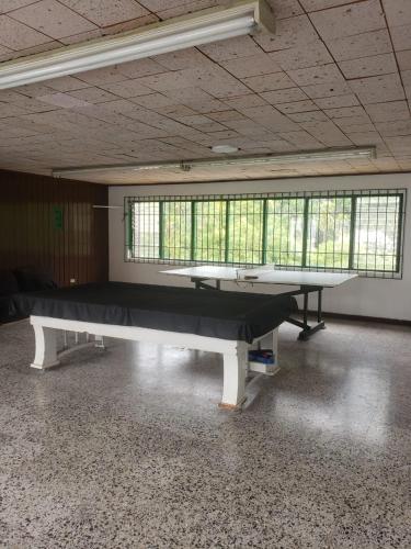 eine Tischtennisplatte in einem leeren Raum mit Fenstern in der Unterkunft QUINTA MARIA LUISA in Melgar