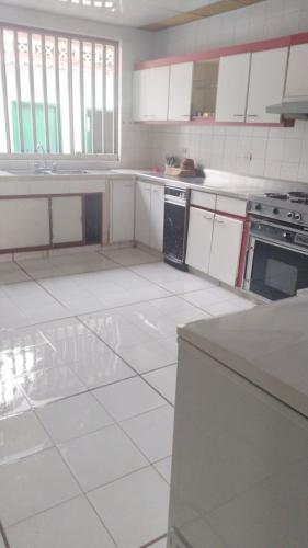 a kitchen with white cabinets and a white tile floor at QUINTA MARIA LUISA in Melgar