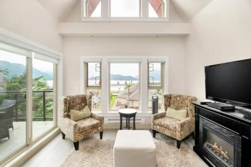 a living room with a fireplace and a flat screen tv at Penthouse Lake Home - 3BR w/Amazing View & Deck! in Harrison Hot Springs