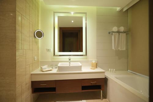 a bathroom with a sink and a tub and a mirror at DoubleTree by Hilton Gurgaon New Delhi NCR in Gurgaon