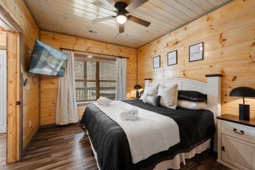 ein Schlafzimmer mit einem Bett in einem Zimmer mit Holzwänden in der Unterkunft 5 Miles to Dollywood & PF, New 2 BR,King Bed,Hot tub,Game Room in Sevierville