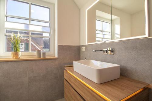 ein Badezimmer mit einem weißen Waschbecken und einem Spiegel in der Unterkunft Villa Küsteneck mit Meerblick und Wellnessbereich in Lohme