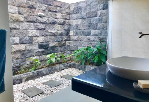 een badkamer met een wastafel en een stenen muur bij Makati Walassey Villa in Karangasem