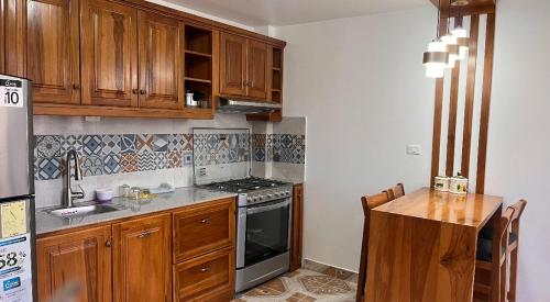 uma cozinha com armários de madeira e um forno com placa de fogão em Kimsa Wasi I em Otavalo