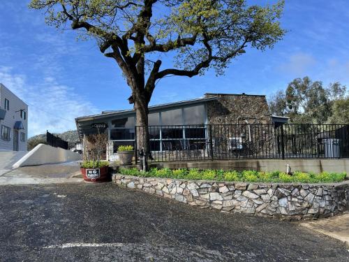 a house with a tree and a stone wall at Sierra Lodge Three Rivers in Three Rivers