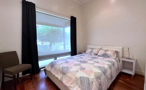 1 dormitorio con cama, ventana y silla en Townhouse 3, en Broken Hill
