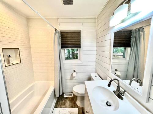 a bathroom with a tub and a toilet and a sink at Newly Renovated- King Suite, near WakeMed & Food in Raleigh