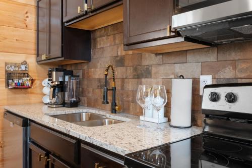 a kitchen with a sink and a counter with wine glasses at Family or couple retreat next to Downtown, Dollywood & Smoky Mountains! in Sevierville