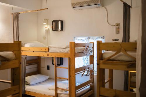 a room with three bunk beds and a fan at Slow Island Hostel in Green Island