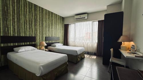 Habitación de hotel con 2 camas y ventana en Bali World Hotel, en Bandung