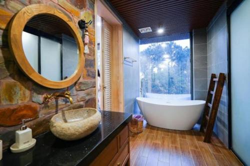 ein Badezimmer mit einer Badewanne und einem großen Spiegel in der Unterkunft Cao Vintage Villa - Venuestay in Tam Ðảo
