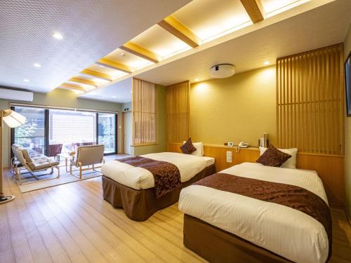 una habitación de hotel con 2 camas y una silla en Hanare no yado Kamigakure, en Takachiho