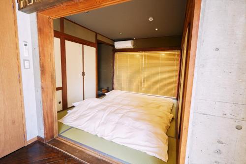 1 cama blanca grande en una habitación pequeña en 「まちの隠れ家ペントハウス」ロフトベッド付き！｜ STAY UWU 003 Penthouse, en Kochi