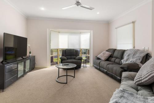 a living room with a couch and a tv at Serenity in Sunny Sawtell in Sawtell