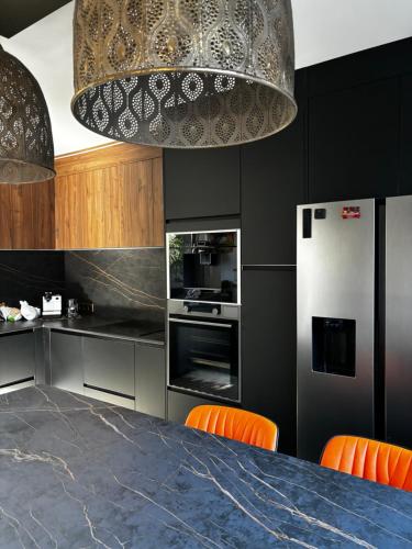 カップブルトンにあるVilla des 4 ventsのキッチン(テーブル、オレンジチェア、冷蔵庫付)