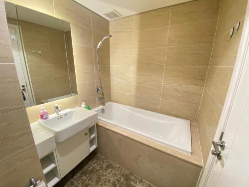 La salle de bains est pourvue d'un lavabo, d'une baignoire et d'un miroir. dans l'établissement D'capitale Trần Duy Hưng Hà Nội 2 Phòng Ngủ Bồn tắm Thư giãn, à Hanoï