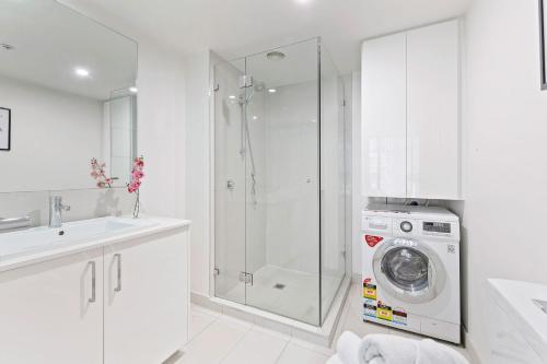y baño blanco con lavadora y ducha. en A Chic Studio Only a 4-min Walk to Victoria Market en Melbourne