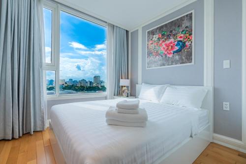 a bedroom with a white bed with a large window at Léman Luxury Apartment District 3 HCMC in Ho Chi Minh City