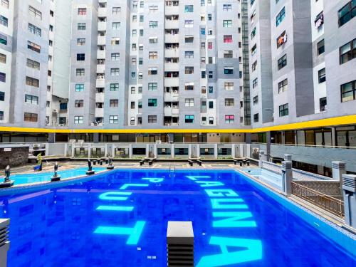 a large swimming pool with tall buildings in the background at Beranda Istirahat 2BR Laguna Pluit in Jakarta