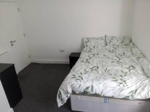 an unmade bed in a bedroom with a night stand at Ensuite Double-bed (G3) close to Burnley city centre in Burnley