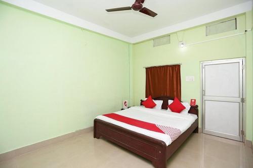 a bedroom with a bed with red pillows and a ceiling fan at Hotel Somnath Guest House ! Puri in Puri